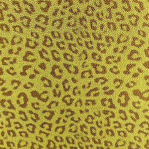 May include: A yellow fabric with a brown leopard print pattern. The fabric is made of a textured material that resembles small beads.