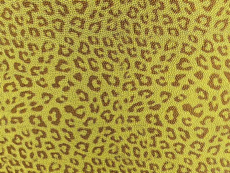 May include: A yellow fabric with a brown leopard print pattern. The fabric is made of a textured material that resembles small beads.