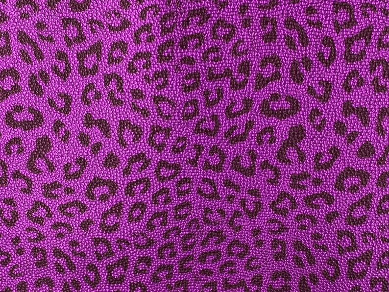 May include: Purple fabric with a leopard print pattern. The fabric has a textured surface.