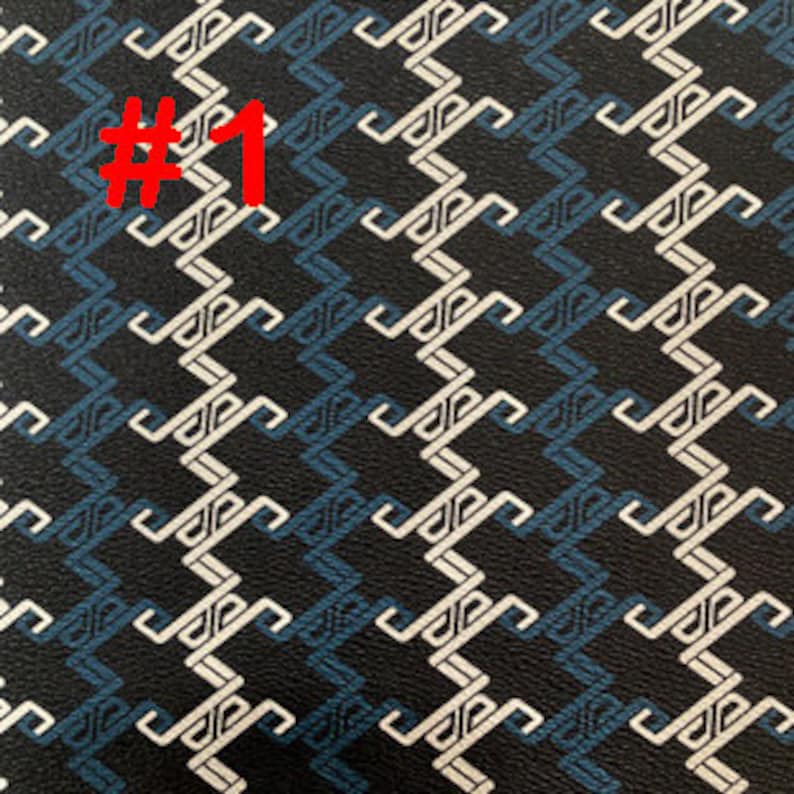 May include: Black fabric with a white and blue geometric pattern. The pattern is a repeating design of interlocking shapes.