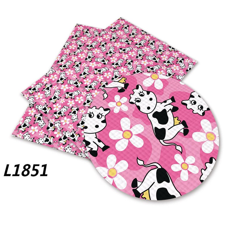 Puede incluir: Tela rosa y blanca con un patr&oacute;n repetido de vacas blancas y negras y flores blancas. La tela es texturizada y tiene un ligero brillo. La tela est&aacute; etiquetada con el n&uacute;mero L1851.