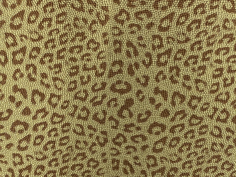 May include: A brown and beige fabric with a leopard print pattern. The fabric has a textured surface.
