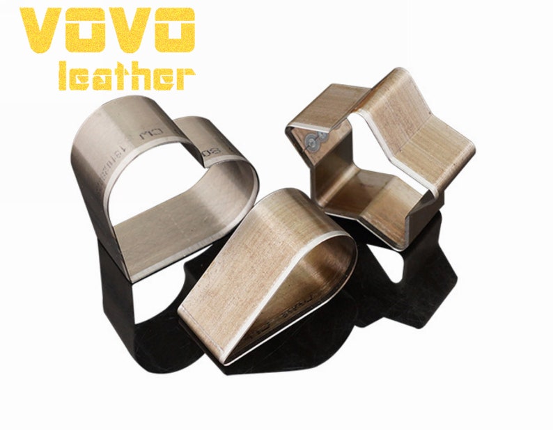 May include: Three metal leather craft punches in the shapes of a heart, a teardrop, and a star. The punches are made of metal and have a wood-like finish.