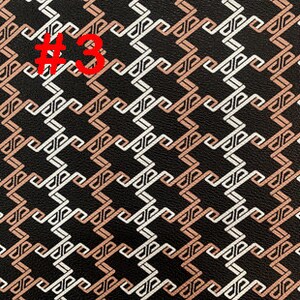 May include: Black fabric with a geometric pattern in white and light brown. The pattern is made up of interlocking squares and rectangles.