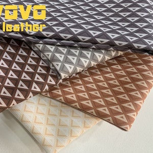 May include: Four fabric swatches with a geometric pattern of white triangles on a brown, orange, grey, and beige background. The swatches are stacked on top of each other. The top swatch has the text "VOVO leather" printed on it.