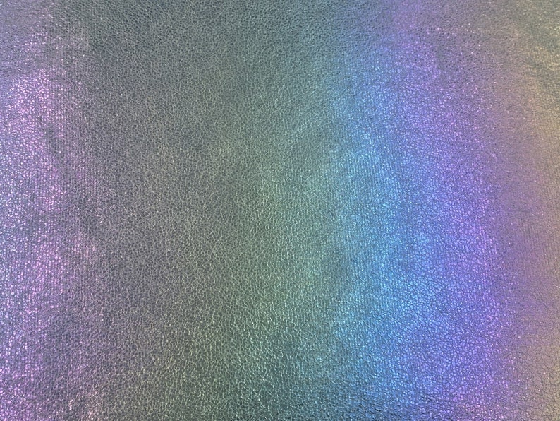 May include: A close-up of a textured, iridescent surface with a rainbow gradient of colors, including purple, blue, green, and yellow.