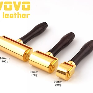 May include: Three gold leather working tools with wooden handles. The tools are different sizes, with the largest being 100mm and 902g, the middle being 60mm and 570g, and the smallest being 26mm and 290g.
