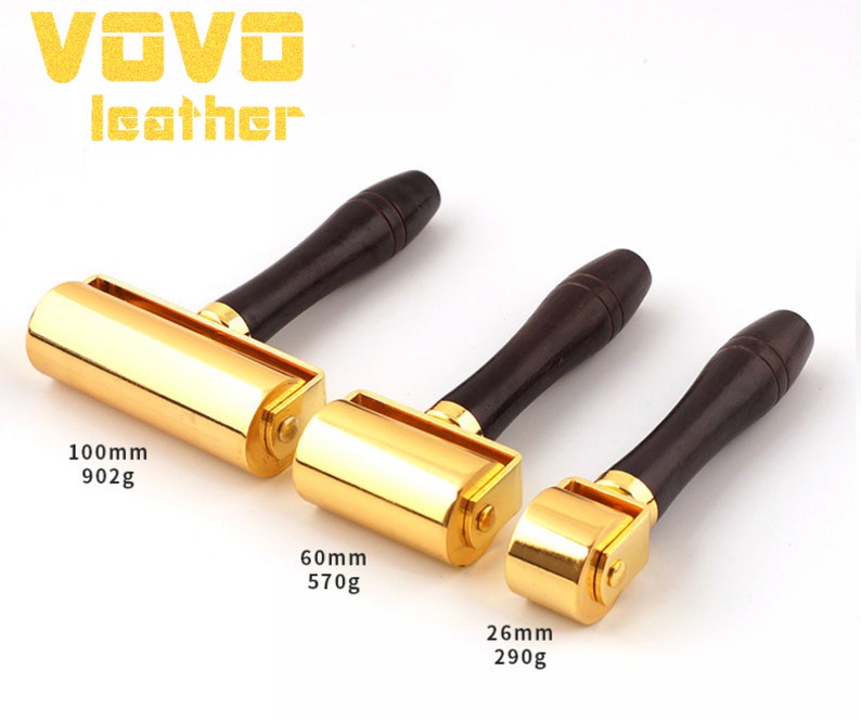 May include: Three gold leather working tools with wooden handles. The tools are different sizes, with the largest being 100mm and 902g, the middle being 60mm and 570g, and the smallest being 26mm and 290g.