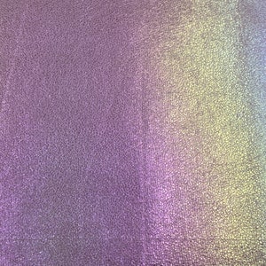 May include: A close-up of a textured, iridescent fabric with a gradient of colors, including purple, blue, green, and yellow.