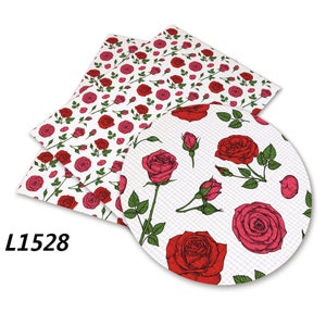 May include: A white fabric sheet with a repeating pattern of red roses and green leaves. The fabric sheet is folded in half and has the text "L1528" printed on the bottom left corner.