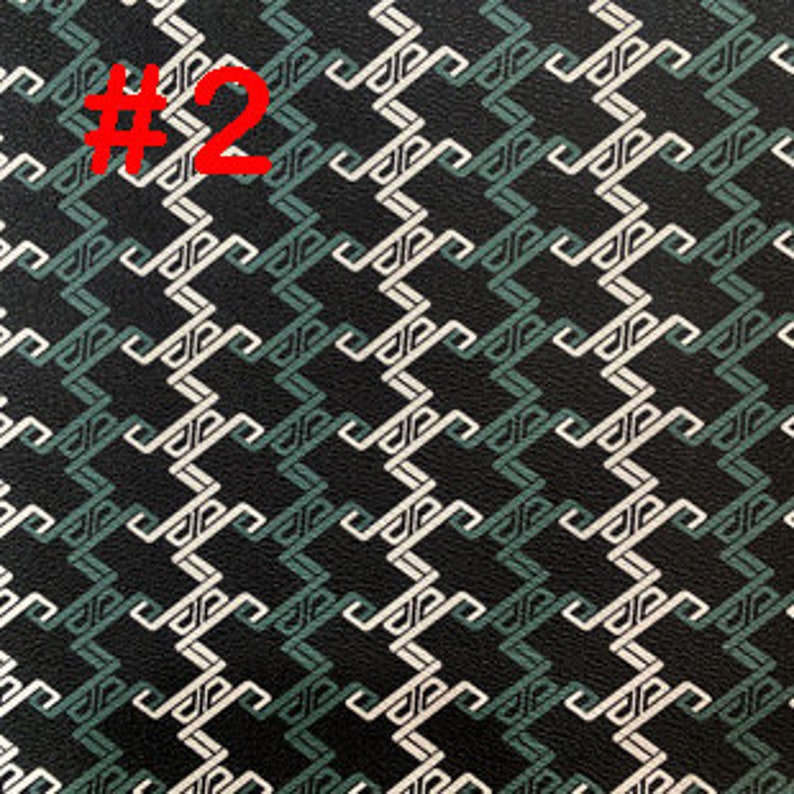 May include: Black fabric with a white and green geometric pattern. The pattern is made up of repeating shapes that resemble a series of interlocking 'S' curves.