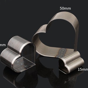 May include: Three metal heart-shaped cookie cutters. The largest cutter is 50mm wide, the middle cutter is 30mm wide, and the smallest cutter is 15mm wide.