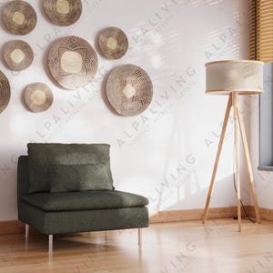 May include: A modern living room with a dark green armchair, wooden floor, and a collection of decorative wall art. The room features a floor lamp, a pendant light, and a large window with blinds. The overall aesthetic is minimalist and stylish.