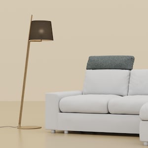 May include: A modern white sectional sofa with a chaise lounge, featuring a gray bolster pillow. A gold floor lamp with a dark brown lampshade stands to the left. The background is a solid beige color.