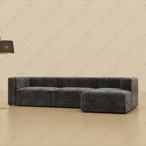 Könnte beinhalten: Ein dunkelgraues Ecksofa mit passendem Hocker. Eine goldfarbene Stehlampe mit rechteckigem Schirm steht links vom Sofa. Die Möbel stehen vor einem neutralen Hintergrund.