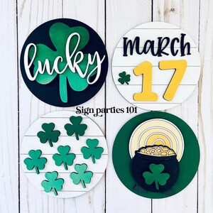 May include: Four round wooden signs with a St. Patrick's Day theme. The signs feature a shamrock, the words "lucky", the date "March 17", and a pot of gold with a rainbow.