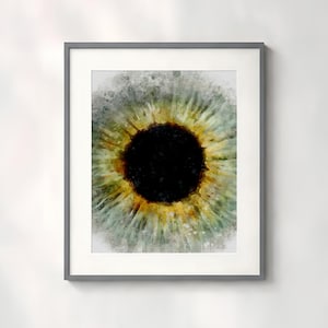 May include: A framed wall art print featuring a watercolor-style illustration of a human eye iris. The central pupil is a solid black circle surrounded by a vibrant ring of golden yellow, transitioning into shades of light green and gray.