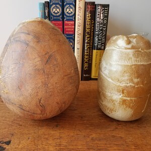 May include: Two ceramic vases, one with a smooth, brown, egg-shaped body and the other with a textured, white and brown, cylindrical body.