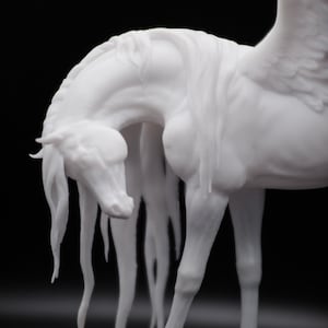以下が含まれることがあります： 黒い背景に、白いペガサスの彫刻。馬の頭は下がり、長いタテガミが首に沿って流れています。翼は詳細で、彫刻は滑らかな仕上がりです。