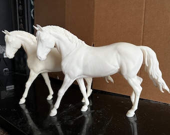 May include: Two white horse figurines, one standing and one walking, are posed together on a black surface.