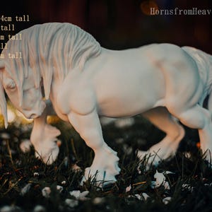 May include: A white horse figurine with a flowing mane and tail, posed in a walking stance. The figurine is approximately 9.4 inches tall (Traditional), with other sizes available. The text "HornsfromHeaven 2026" is visible.