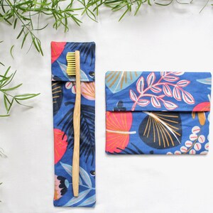 May include: Two blue fabric pouches with a floral pattern. One pouch contains a wooden toothbrush with yellow bristles.