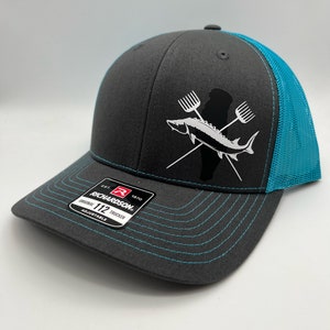 May include: A gray and turquoise trucker hat with a white logo of a fish and crossed fishing poles. The logo says "Richardson 112 Trucker Adjustable".
