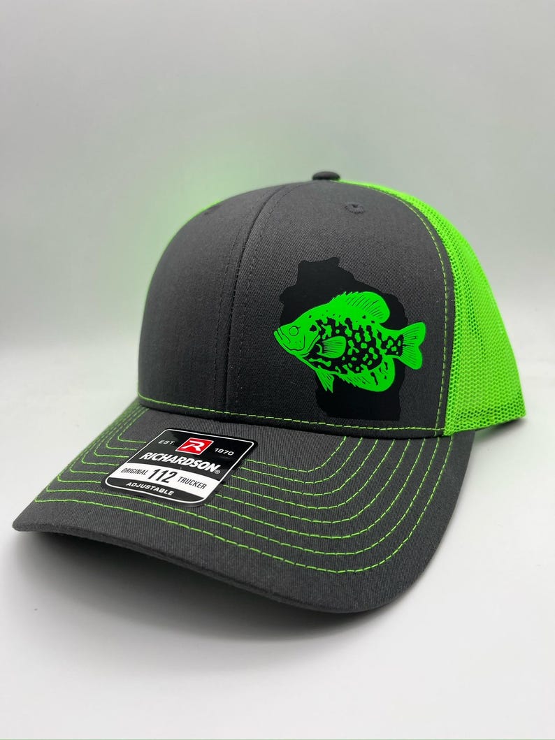 May include: A gray Richardson 112 trucker hat with a neon green fish graphic. The hat features a neon green mesh back, brim, and stitching. The front of the hat has a black outline of a fish with a neon green fish inside.