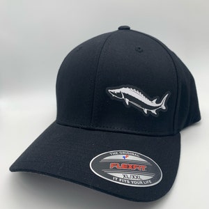 May include: Black Flexfit baseball cap with a white and gray sturgeon fish graphic on the front. The cap has a curved brim and the Flexfit logo on the brim. The hat is size XL/XXL.
