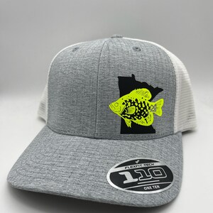 May include: A gray Flexfit Tech 110 hat with a white mesh back. The front features a black silhouette of Minnesota with a neon yellow fish graphic. The hat has a curved brim and a Flexfit Tech 110 One Ten label.
