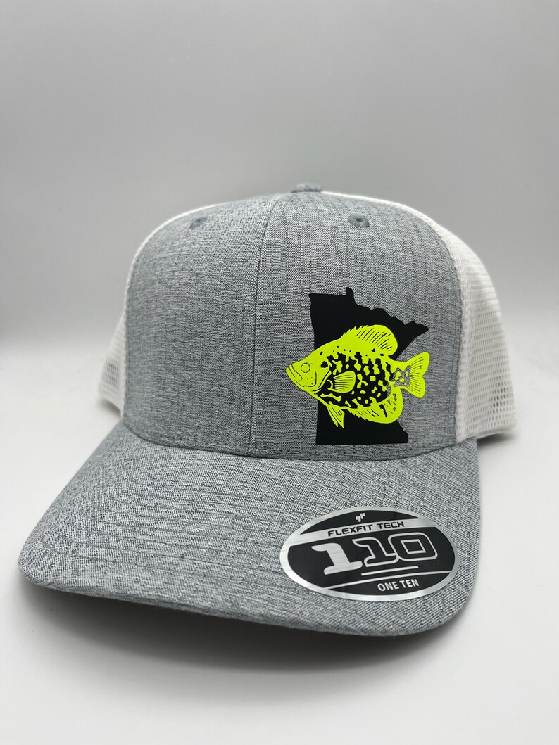 May include: A gray Flexfit Tech 110 hat with a white mesh back. The front features a black silhouette of Minnesota with a neon yellow fish graphic. The hat has a curved brim and a Flexfit Tech 110 One Ten label.