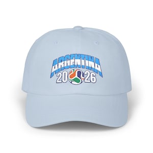 May include: A light blue baseball cap featuring an embroidered design on the front. The text reads ARGENTINA in a blue and white striped font, positioned above the numbers 20 and 26 with a colorful soccer ball graphic in the center.