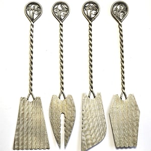 May include: Four silver serving utensils with ornate filigree tops and twisted handles. Each utensil has a different blade shape, including a triangle, a heart, and a curved edge. The blades have a textured, wavy pattern.
