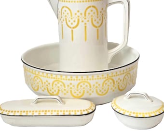 Op de afbeelding: Een witte porseleinen badkamerset met een kan, een kom, een zeepbakje en een pot met deksel. De set heeft een geel en zwart geometrisch patroon.