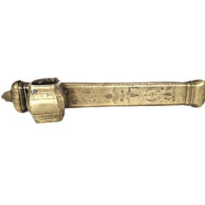 Può includere: Calamaio antico in ottone con corpo rettangolare e incisioni floreali ornate. Il calamaio presenta una piccola sommità decorativa e un lungo manico rettangolare. L'ottone ha una calda patina invecchiata. Un classico accessorio di scrittura.