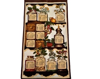 May include: A brown kitchen towel with a vintage calendar design featuring herbs and spices. Each month is represented by a different herb or spice, with the name of the month and the year 1983 printed on each calendar.