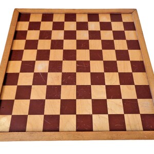 May include: A wooden chessboard with a brown and beige checkered pattern. The board has a wooden frame.