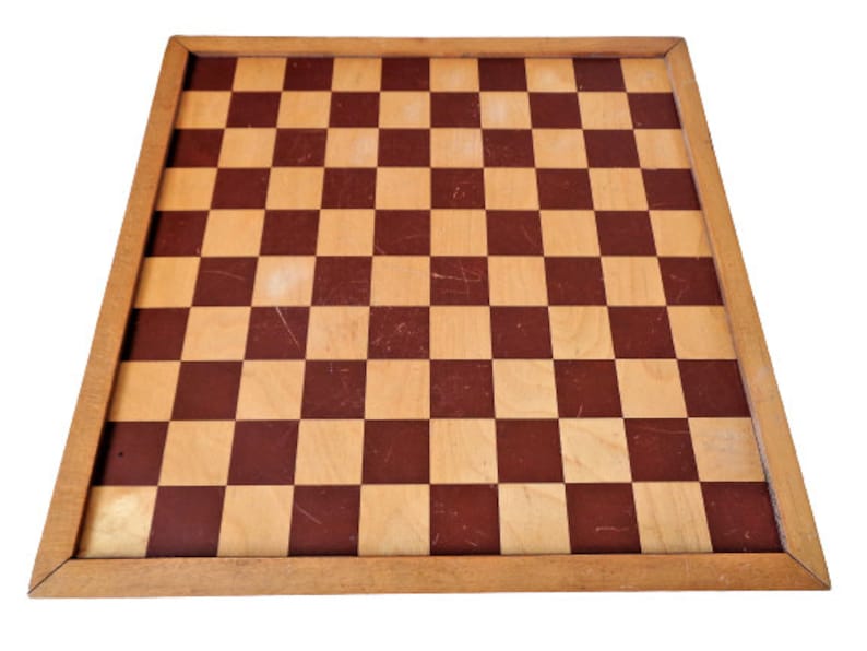 May include: A wooden chessboard with a brown and beige checkered pattern. The board has a wooden frame.