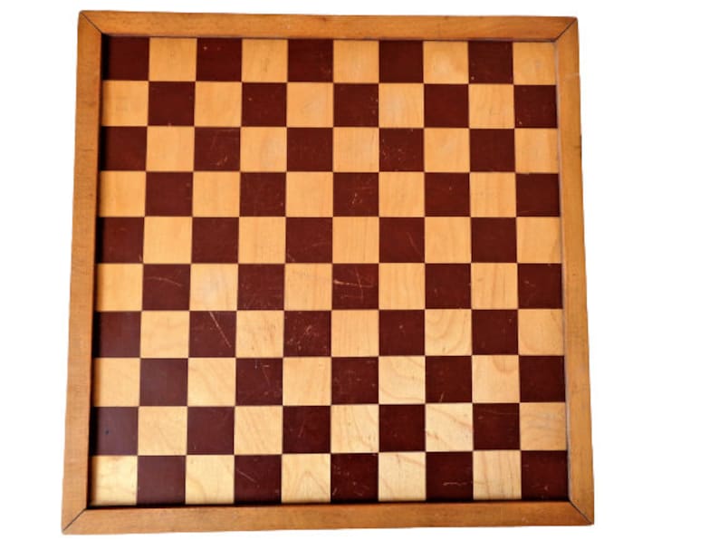 May include: A wooden chessboard with a brown and tan checkered pattern. The board is surrounded by a wooden frame.