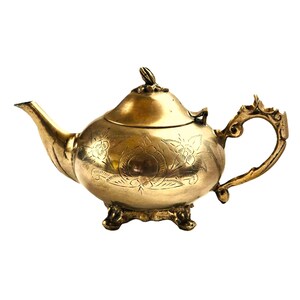 Könnte beinhalten: Eine goldene Teekanne mit floralem Muster und Deckel. Die Teekanne hat einen runden Korpus und einen geschwungenen Ausguss. Sie hat drei Beine und einen Henkel.