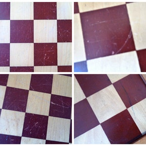 May include: A close-up of a wooden checkerboard with red and white squares. The board is worn and has scratches on the surface.