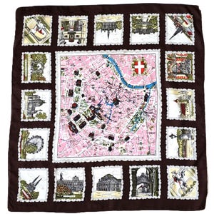 May include: A brown silk scarf with a pink map design in the center, surrounded by postage stamp-like images of landmarks. The scarf has a white lace-like border and is a square shape.