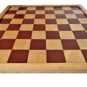 May include: A wooden chessboard with a brown and natural wood checkered pattern. The board has a simple wooden frame.