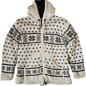 May include: A cream-colored hooded sweater with a black and white geometric pattern. The sweater has a zipper closure and two front pockets.