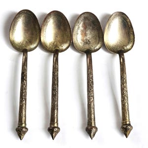 Puede incluir: Juego de cuatro cucharas de plata con mangos adornados. Las cucharas tienen un cuenco redondeado y un extremo puntiagudo. Los mangos están decorados con intrincados motivos florales.