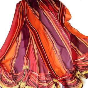 May include: A sheer orange and burgundy striped scarf with a red and gold patterned border. The scarf is made of a lightweight fabric and has a flowing drape.