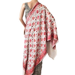 May include: White shawl with a floral pattern in shades of pink and red. The shawl has a delicate embroidered border.