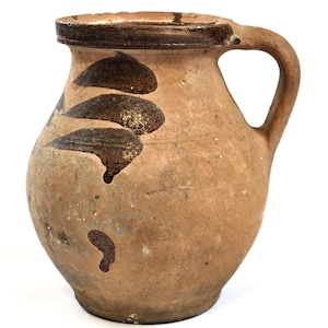 Puede incluir: Jarra rústica de cerámica con cuerpo redondeado y asa curva. La jarra es principalmente de color marrón claro, con diseños oscuros en forma de hoja marrón y un borde marrón oscuro. Capacidad aproximada de 1 litro.