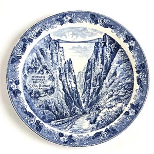 Może przedstawiać: Niebieski i biały ceramiczny talerz z obrazkiem mostu Royal Gorge w Kolorado. Na talerzu nadrukowany jest tekst "World's Highest Bridge, Royal Gorge, Colorado".