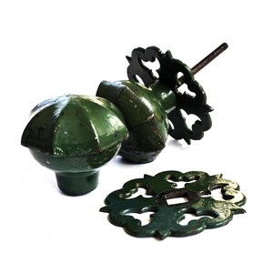 May include: A set of antique door knobs in a dark green color. The knobs are made of metal and have a decorative design. The set includes a round knob, a square knob, and a decorative plate.